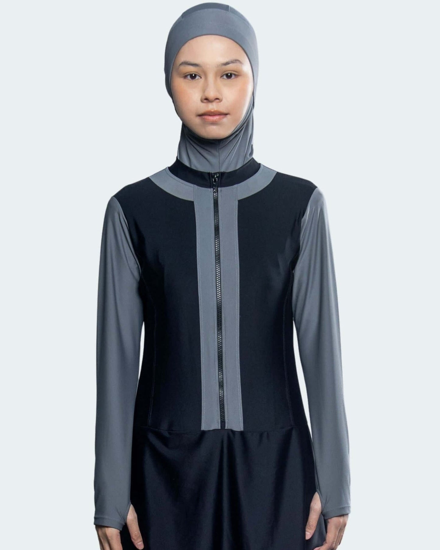 Person wearing a black and gray outfit with a matching headscarf on a white background