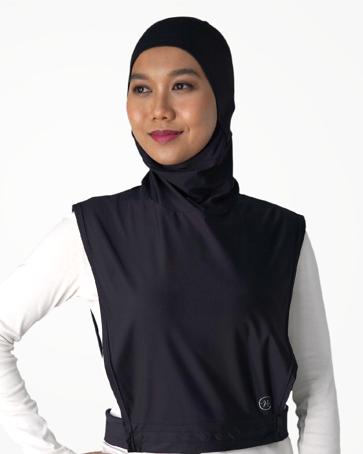 A woman wearing a black hijab  with an elastic band around the face circumference and adjustable buttons at the waist straps, designed for secure coverage during water and land physical activities.